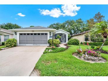 Charming home with a lush, landscaped front yard and screened two-car garage at 27302 Stoney Brook Dr, Leesburg, FL 34748