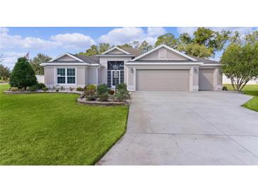 Charming single-story home with a well-manicured lawn, colorful flowerbeds, and a three car garage at 2954 Heiny Pl, The Villages, FL 32163