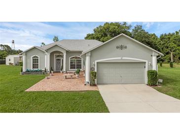 Charming single-story home with a well-manicured lawn and a brick-paved seating area at 316 Dupont Cir, Howey In The Hills, FL 34737