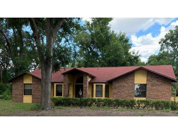 Charming single-story home with brick facade, red roof, and manicured front yard landscaping at 37236 Cherry Lake Rd, Fruitland Park, FL 34731