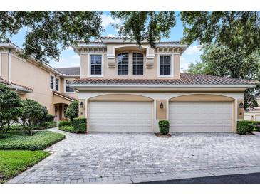 Charming two-story home with a red tile roof and a three car garage on a brick driveway at 52 Camino Real Blvd, Howey In The Hills, FL 34737