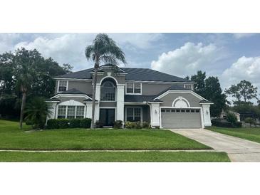 Charming two-story home with attached garage and well-manicured front lawn and mature palm tree at 633 Grand Cypress Pt, Sanford, FL 32771