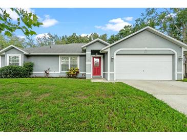 Charming single-story home featuring a well-manicured lawn and a bright red front door at 815 Forestwood Dr, Minneola, FL 34715