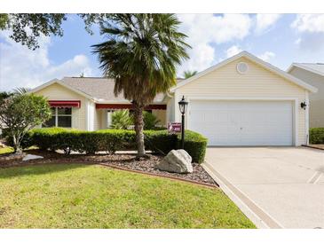 Inviting single-story home with manicured landscaping, a two-car garage, and a charming front yard at 891 Lucky Ln, The Villages, FL 32162