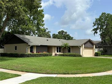 Charming single-story home with a lush, green lawn and mature trees at 9375 Woodbreeze Blvd, Windermere, FL 34786