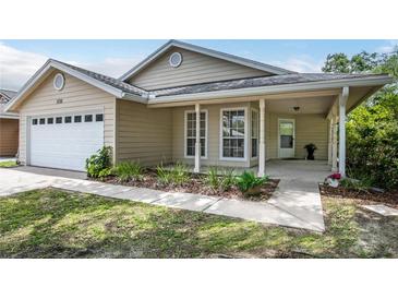 Charming single-story home with a covered front porch, attached garage, and nicely landscaped front yard at 1730 Dorset Dr, Mount Dora, FL 32757
