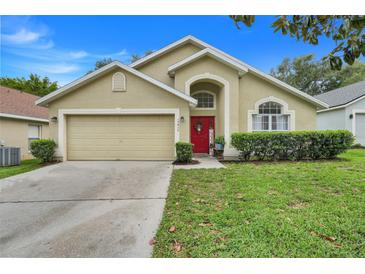 Charming single-story home featuring a well-maintained lawn, a two-car garage, and a welcoming red front door at 17428 Woodfair Dr, Clermont, FL 34711