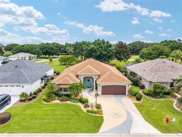 Beautiful home with a blue front door, well-manicured lawn, and a decorative driveway at 219 Carrera Dr, The Villages, FL 32159