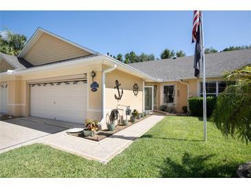 Charming home exterior with a two-car garage, well-maintained lawn, and nautical decorations at 26917 White Plains Way, Leesburg, FL 34748