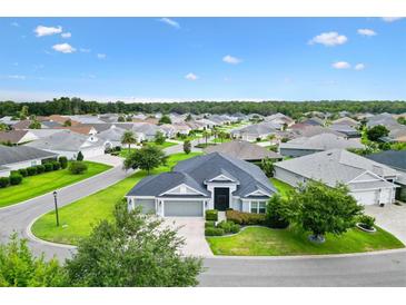 Stunning aerial view of a well-maintained home with lush landscaping and a three-car garage in a desirable community at 5868 Wood Stork Way, The Villages, FL 32163