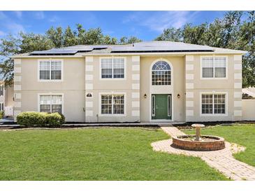 Charming two-story home featuring a well-maintained lawn, green door, and solar panels at 800 Daybreak Dr, Fruitland Park, FL 34731