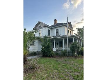 Exterior of a two-story home with a covered front porch and classic architectural details needing a bit of TLC at 110 S Trowell Ave, Umatilla, FL 32784