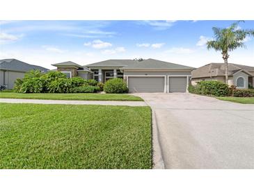 Charming single-story home with a lush, landscaped front yard and a three-car garage at 1351 Legendary Blvd, Clermont, FL 34711