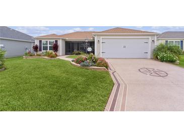 Charming home featuring a well-manicured lawn, decorative driveway, and beautiful flower beds at 1721 Germakian Ln, The Villages, FL 32163