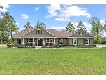 Inviting single story home featuring an expansive lawn, rocking chair front porch, and neutral exterior at 23247 Lake Seneca Rd, Eustis, FL 32736