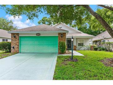 Charming single-story home with a green garage door, brick accents and well-maintained lawn at 25025 Cranes Roost Cir, Leesburg, FL 34748