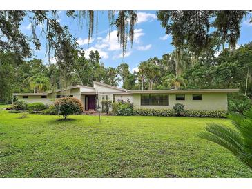 Charming single-story home featuring a lush green lawn and mature landscaping, offering serene curb appeal at 27113 Robertson Rd, Yalaha, FL 34797
