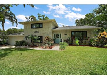 Charming two-story home with a well-manicured lawn, mature trees and a brick facade at 27212 Orange Ave, Yalaha, FL 34797