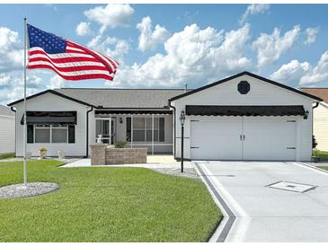 Charming single-story home with a well-manicured lawn, brick accents, and a large American flag in the front yard at 3237 Atwell Ave, The Villages, FL 32162