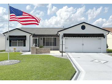 Charming one-story home with a manicured lawn, an American flag, a two-car garage, and a delightful screened in porch at 3237 Atwell Ave, The Villages, FL 32162
