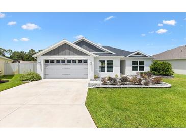 Charming single-story home with a well-manicured lawn and a gray two-car garage, perfect for suburban living at 4157 Tiedemann Loop, The Villages, FL 32163