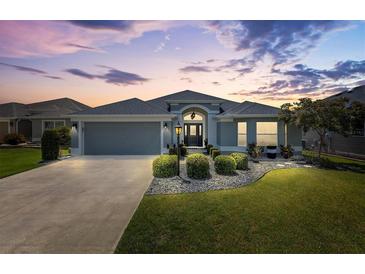 Beautiful home exterior featuring manicured landscaping, neutral paint and elegant architectural details at dusk at 3566 Gentle Ter, The Villages, FL 32163