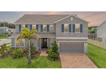 Charming two-story home with a brick driveway, blue shutters, and tropical landscaping at 391 Cheeota Ct, Minneola, FL 34715