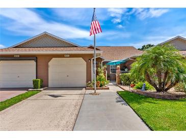 Charming home featuring an American flag, manicured landscaping and attached two car garage at 5512 Rosewall Cir, Leesburg, FL 34748