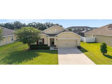 Charming one-story home featuring a well-manicured lawn and attached two-car garage at 9785 Pepper Tree Trl, Wildwood, FL 34785
