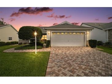 Charming single-story home featuring a brick driveway, well-manicured lawn, and an attached two-car garage at 1007 Diego Ct, The Villages, FL 32159