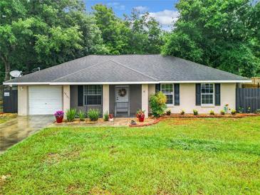 Charming single-story home featuring lush landscaping, a gray roof and a welcoming entrance, complemented by a well-maintained front yard at 12181 Se 87Th Ct, Belleview, FL 34420