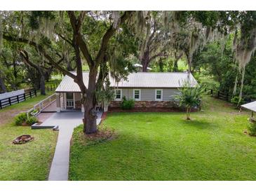 Inviting home boasts lush lawn, stone accents, and a metal roof, nestled under mature trees with Spanish moss at 1436 Spring Lake Rd, Fruitland Park, FL 34731