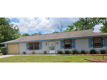 Charming single-story home featuring light blue siding and well-maintained landscaping at 235 Rockmoore Ct, Deland, FL 32720