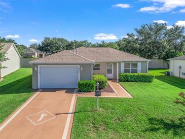 Charming single-story home with a well-manicured lawn and attached garage, located in a quiet neighborhood with mature trees at 2369 Five Forks Trl, The Villages, FL 32162