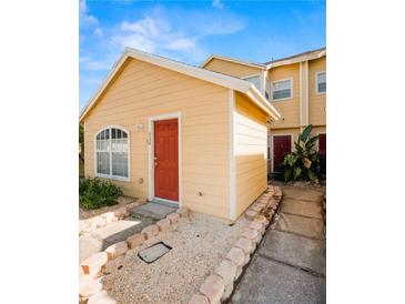 Charming yellow home with a red front door and well-maintained landscaping at 624 Australian Way, Davenport, FL 33897