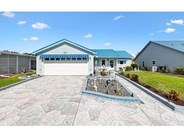 Charming single-story home with blue awnings, an attached garage, and a beautifully landscaped front yard at 714 Prado Dr, The Villages, FL 32159