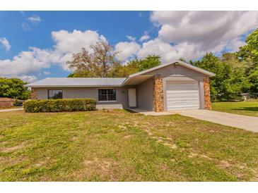 Charming single-story home featuring stone accents, a metal roof, and a well-maintained front lawn at 7211 Se 120Th St, Belleview, FL 34420