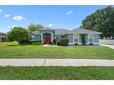 Charming single-story home featuring a red front door, well-manicured lawn, and mature landscaping at 14708 Timucua Pl, Clermont, FL 34711