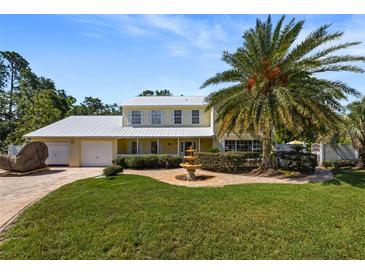Inviting home featuring a well manicured lawn, mature palm trees, fountain, and a convenient two car garage at 15733 Tower View Dr, Clermont, FL 34711