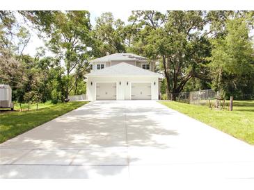 Two-story home with a two-car garage and a long driveway, surrounded by mature trees at 2114 Waitman Ave Waitman, Leesburg, FL 34748