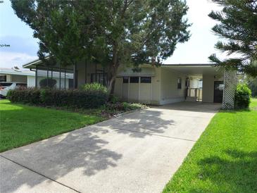 Charming home with well-manicured lawn, mature trees, and covered carport at 432 Santa Fe E Rd, Tavares, FL 32778