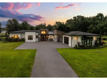 Striking modern home with lush landscaping, a paved driveway, and a welcoming entrance at sunset at 6031 Dora Dr, Mount Dora, FL 32757