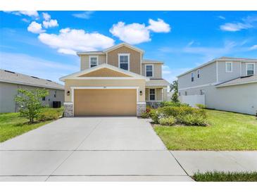 Charming two-story home featuring a tan exterior, landscaped yard, and a spacious two-car garage at 853 Blue Creek Dr, Haines City, FL 33844