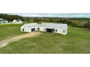 Expansive modern home with a metal roof surrounded by an open green lawn at 10711 County Road 561, Clermont, FL 34711