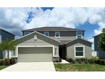 Two-story home featuring neutral paint, two car garage, manicured landscaping, and a concrete driveway at 1138 Calico Pointe Cir, Groveland, FL 34736