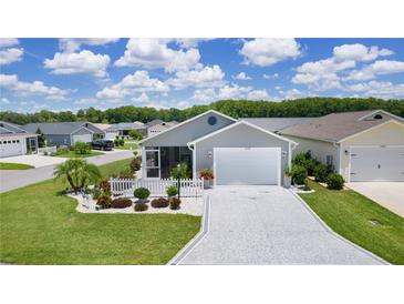 Charming home featuring an attached garage, manicured lawn, and decorative white picket fence surrounding a landscaped garden at 1478 Erika Pl, The Villages, FL 32163