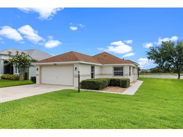 Charming single-story home with a well-manicured lawn and attached garage, near a scenic lake at 5715 Illumination Ln, Leesburg, FL 34748