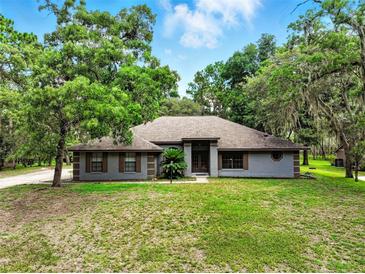 Charming single-story home with mature trees, a well-maintained lawn, and neutral colored exterior at 1053 Cavern Dr, Apopka, FL 32712