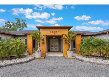 Inviting front entrance with stone, wood accents, lush landscaping, and an elegant glass front door at 14227 County Road 455, Clermont, FL 34711