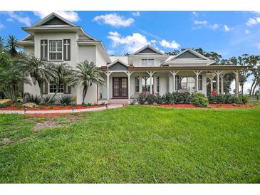 Stunning two-story home featuring a large front yard, brick path, and inviting wrap-around porch at 15104 County Road 48, Astatula, FL 34705